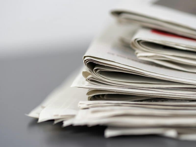 A stack of newspapers on a black table.