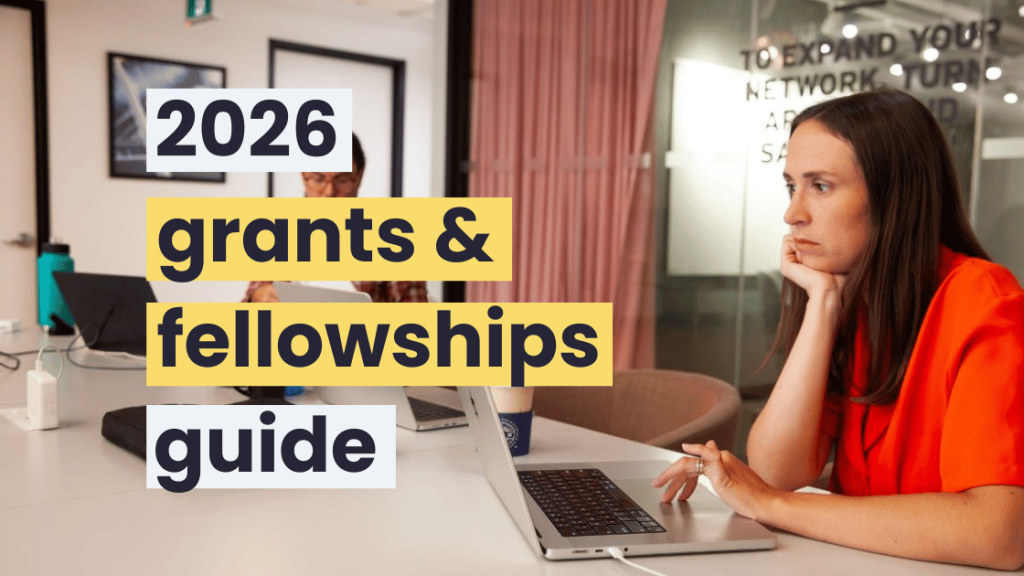 A woman with long brown hair and wearing a red shirt using a laptop in a meeting room.