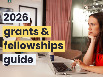 A woman with long brown hair and wearing a red shirt using a laptop in a meeting room.