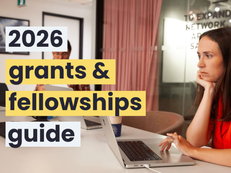 A woman with long brown hair and wearing a red shirt using a laptop in a meeting room.