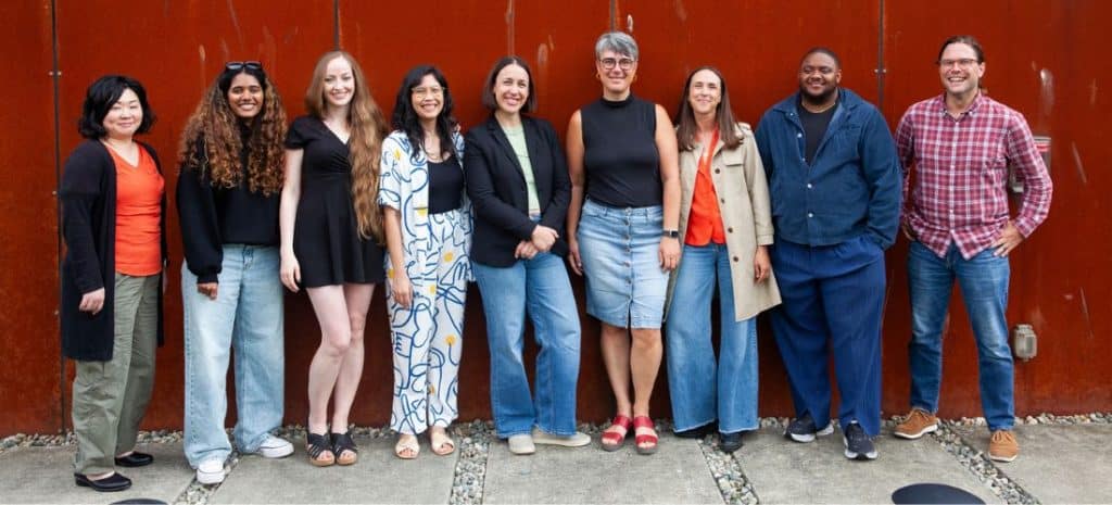 Group of Indiegraf team members gathered in an open, bright office space, smiling and posing casually — Indiegraf pricing page.